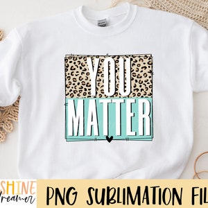 May include: White sweatshirt with a graphic design that says "You Matter" in black text. The text is surrounded by a leopard print pattern and a light blue rectangle.