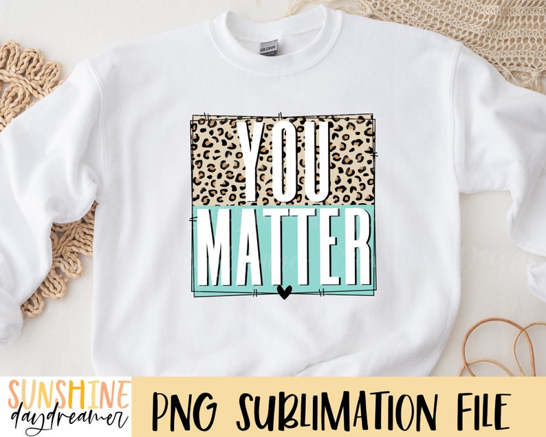 May include: White sweatshirt with a graphic design that says "You Matter" in black text. The text is surrounded by a leopard print pattern and a light blue rectangle.