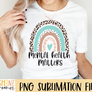 May include: A white t-shirt with a rainbow design featuring a heart and the text "Mental Health Matters".