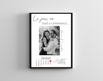 May include: A black and white photo of a couple on their wedding day. The photo is framed in a black frame with a white background. The text "Le jour où tout a commencé..." is written above the photo. The text "Aria & Louka" is written to the right of the photo. The text "Vendredi Juillet 2023" is written below the photo. A red heart is next to the text "Juillet".