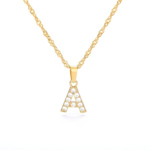 May include: A gold chain necklace with a pendant in the shape of the letter A. The pendant is encrusted with clear cubic zirconia stones.