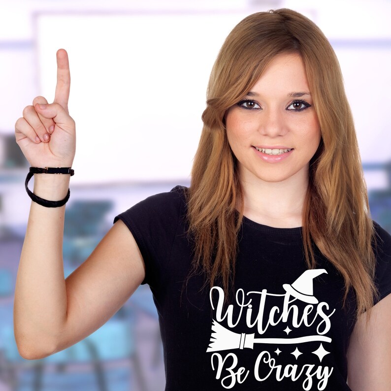 May include: A black t-shirt with a white graphic design that says "Witches Be Crazy" with a witch's hat and broom.