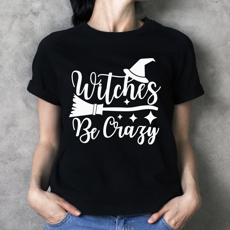 May include: Black t-shirt with white text that reads "Witches Be Crazy" with a witch's hat and broom graphic.