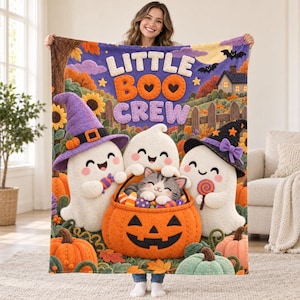 May include: A soft fleece blanket featuring the text LITTLE BOO CREW, three white ghosts, and a gray tabby kitten sitting in a large orange jack-o'-lantern pumpkin bucket. The scene includes sunflowers, autumn leaves, a wooden fence, and a house.