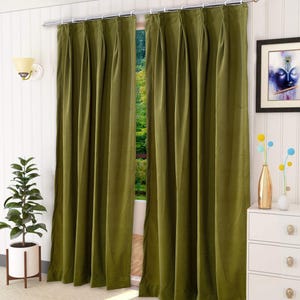 May include: A pair of floor-length olive green curtains featuring a pinch pleat header design. The curtains are hung on a silver metal rod with white rings, creating vertical folds that extend from the top to the bottom of the fabric panels.