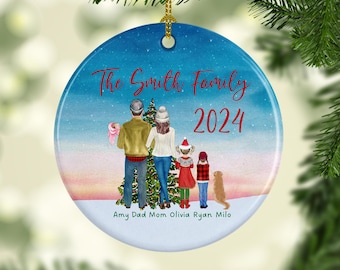 May include: A personalized Christmas ornament featuring a family of five standing in front of a Christmas tree. The ornament is blue with a white snowy background and the text "The Smith Family 2024" in red. The names "Amy, Dad, Mom, Olivia, Ryan, Milo" are written below the family.