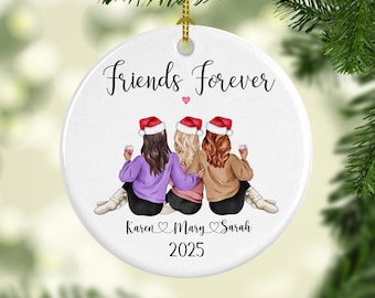 Puede incluir: Adorno navideño redondo de cerámica blanca con el texto "Friends Forever" y los nombres Karen, Mary y Sarah, junto con el año 2025. El adorno presenta una ilustración de tres amigas con gorros de Papá Noel, sosteniendo copas de vino.