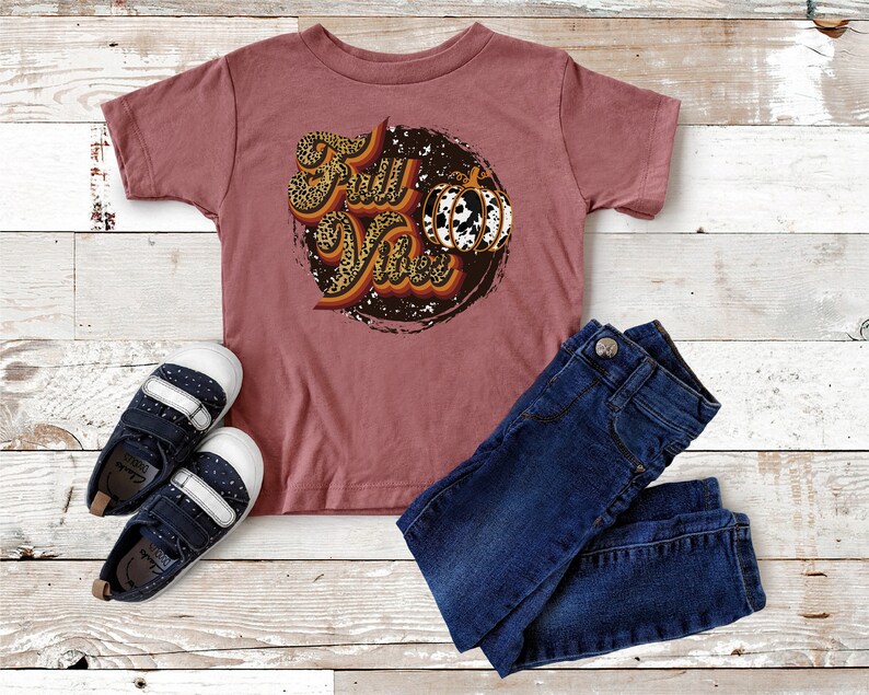 May include: A maroon short-sleeved t-shirt with a graphic of a pumpkin and the text "Fall Vibes" in a leopard print design.
