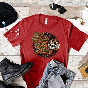 May include: Red t-shirt with a graphic design of the words "Fall Vibes" in a retro font with a leopard print pattern and a pumpkin with a cow print pattern.