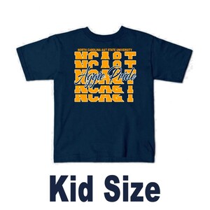 May include: A navy blue short-sleeve t-shirt featuring the text North Carolina A&T State University in small letters above a repeating yellow block pattern of NCA&T and the white cursive script text Aggie Pride centered on the front.
