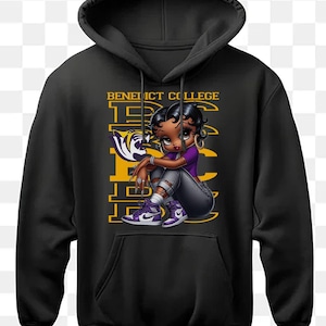 May include: Black hoodie with a yellow and purple graphic of a cartoon woman wearing a purple shirt and jeans. The graphic includes the text "Benedict College" and a stylized "BC" logo.