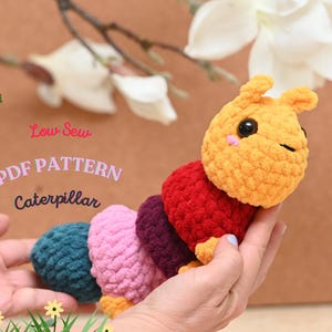 Puede incluir: Un juguete de oruga de crochet colorido con una cabeza amarilla y ojos negros. El juguete está siendo sostenido en la mano de una persona. El texto "Low Sew PDF PATTERN Caterpillar" es visible en la imagen.