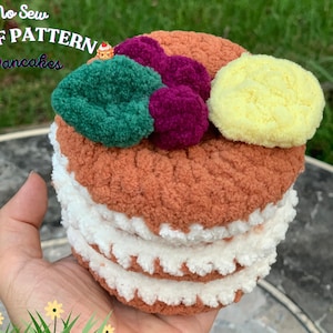 Könnte beinhalten: No Sew PDF Muster Pancakes - Ein gehäkelter Stapel Pfannkuchen mit grünen, lila und gelben Garn-Dekorationen.