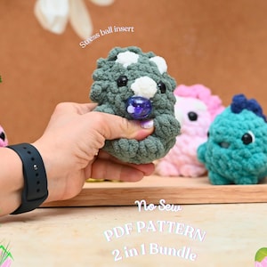 Könnte beinhalten: Gehäkelte Dinosaurier-Stressbälle in Grün, Rosa und Blau. Der grüne Dinosaurier wird in einer Hand gehalten und zeigt seine weißen Punkte und einen blauen, marmorähnlichen Einsatz. Das Bild enthält den Text "No Sew PDF PATTERN 2 in 1 Bundle."