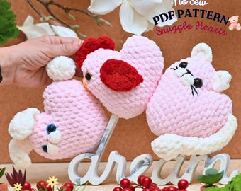 May include: Three pink crocheted heart-shaped stuffed animals with different animal faces. The animals are a chick, a cat, and a bunny. The text "No Sew PDF PATTERN Snuggle Hearts" is in the top right corner of the image.