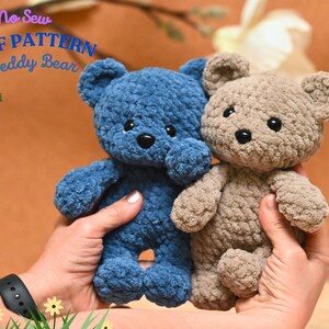 Peut inclure: Deux ours en peluche crochet&eacute;s, l'un bleu et l'autre brun, sont tenus dans les mains d'une personne. Les ours sont faits avec un fil textur&eacute; et ont des yeux noirs. Le texte "No Sew PDF PATTERN Teddy Bear" est visible en arri&egrave;re-plan.