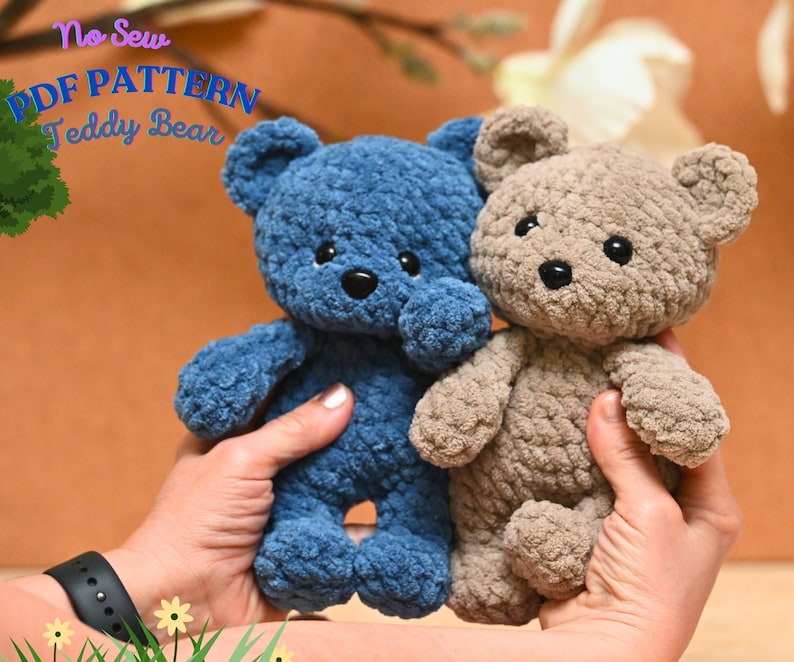 Peut inclure: Deux ours en peluche crochet&eacute;s, l'un bleu et l'autre brun, sont tenus dans les mains d'une personne. Les ours sont faits avec un fil textur&eacute; et ont des yeux noirs. Le texte "No Sew PDF PATTERN Teddy Bear" est visible en arri&egrave;re-plan.