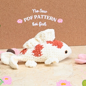 May include: A crocheted koi fish amigurumi pattern, with the words "No Sew PDF PATTERN koi fish" above it. The fish is white with orange and red accents, and is lying on a light brown surface.