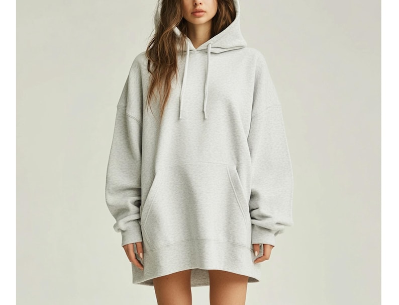 May include: A gray oversized hoodie with a drawstring hood. The hoodie has a kangaroo pocket and long sleeves.