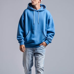 May include: A blue hooded sweatshirt with a pouch pocket and white drawstrings.
