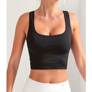 May include: Black cropped tank top with a square neckline. The top is made of a soft, stretchy fabric.