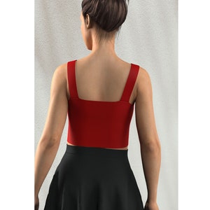 May include: A red cropped tank top with thin straps. The top is sleeveless and has a square neckline.
