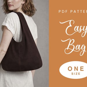Op de afbeelding: Een donkerbruine schoudertas met een gebogen ontwerp is te zien in deze afbeelding. De tas wordt over de schouder gedragen. De tekst "Easy Bag" is geschreven in een sierlijk lettertype. De tekst "ONE SIZE" staat in een witte ovaal.