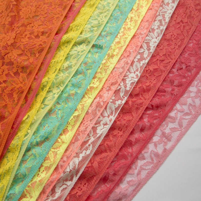 May include: A collection of colorful lace trims in various shades of orange, yellow, green, pink, and red. The lace trims are arranged in a fan shape, with the darkest color at the top and the lightest color at the bottom.