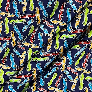 May include: A navy blue fabric with a repeating pattern of colorful race cars. The cars are yellow, red, green, and blue with black wheels and white details.