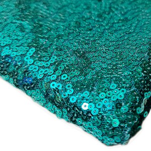 May include: Teal blue fabric with sequins. The sequins are small and round, and they are arranged in a close-packed pattern.