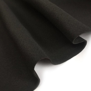 May include: Black felt fabric with a soft, fuzzy texture. The fabric is folded and draped, showing its smooth surface.