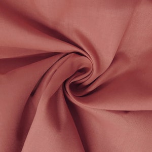 May include: A close-up of a soft, smooth, and slightly textured fabric in a deep, rich, reddish-brown colour. The fabric is folded and draped, creating a luxurious and elegant look.