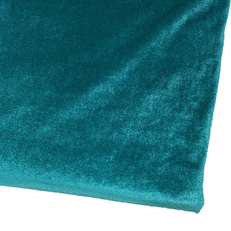 May include: A close-up of a teal blue velvet fabric. The fabric has a soft, plush texture.