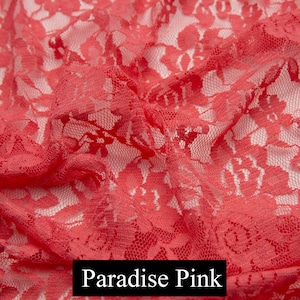 May include: Close-up of a coral pink lace fabric with a delicate floral pattern. The fabric is soft and sheer, with a slightly textured surface. Paradise Pink.