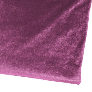 May include: A close-up of a piece of soft, plush fabric in a deep purple hue. The fabric has a velvety texture and a subtle sheen.