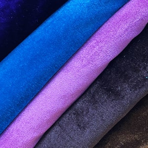 May include: A stack of fabric swatches in various shades of blue, purple, and brown. The fabric has a soft, velvety texture.