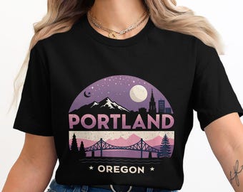 Könnte beinhalten: Schwarzes T-Shirt mit einem lila und pinkfarbenen Grafikdesign einer Stadtlandschaft mit einer Brücke und dem Text "PORTLAND OREGON".