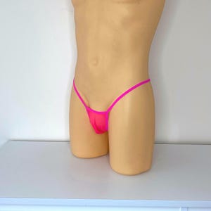 May include: Pink mesh underwear with thin straps. The underwear is on a mannequin.