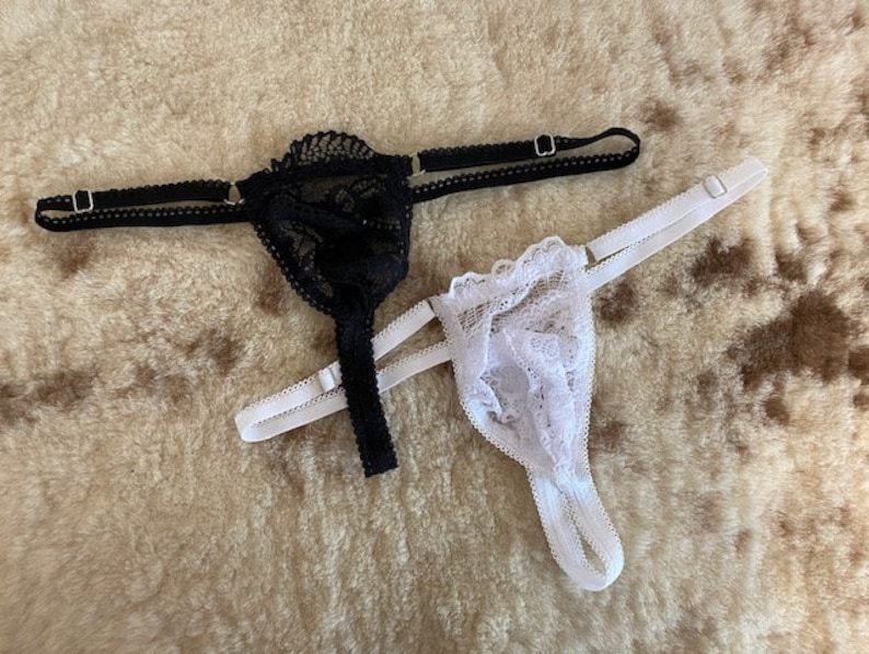 Op de afbeelding: Twee paar zwarte en witte kanten lingerie. Het ene paar is zwart met een delicaat bloemenpatroon en het andere is wit met een gerimpeld ontwerp.
