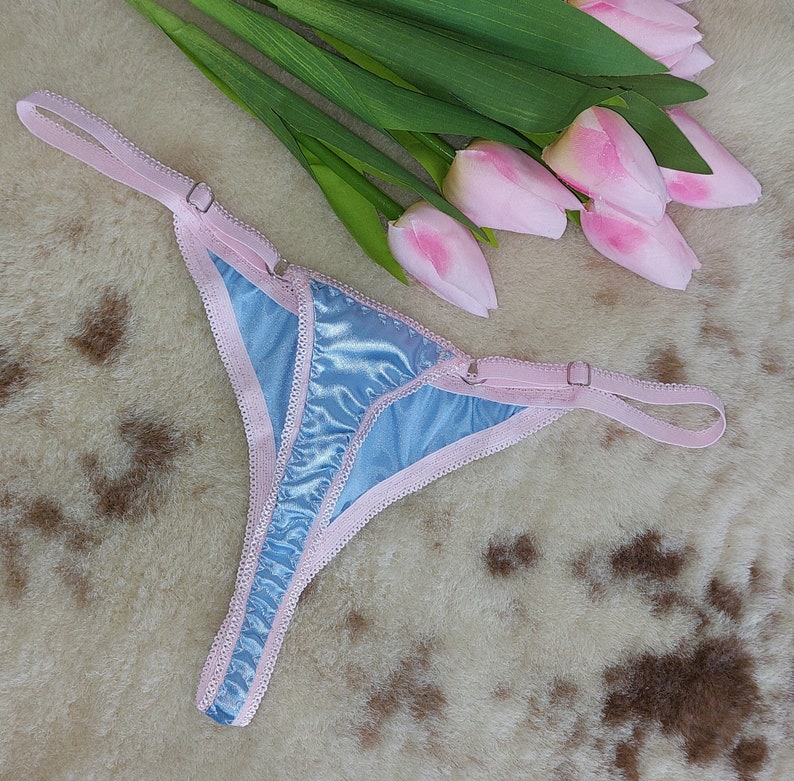 May include: Light blue satin lingerie with pink trim and adjustable straps.