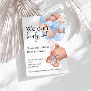 May include: A rectangular baby shower invitation card featuring a watercolor illustration of a brown teddy bear holding a cluster of light blue and tan balloons. The text reads We can bearly wait! Please join us for a BABY SHOWER on Saturday August 2nd at 2PM at 123 Baby Lane, City, LEI 234. Please RSVP to Charlotte on 07123 456789.