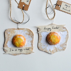 Dos huevos fritos hechos de papel y cartón como decoración de reciclaje en Semana Santa en el set: "Feliz Pascua" y "Estoy tan citado por huevos"