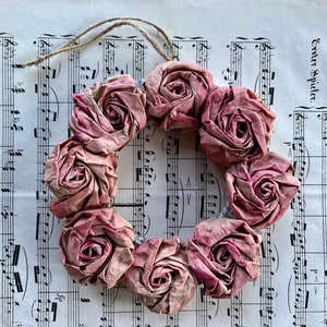 Corona de cartón reciclado de color rosa viejo con flores de rosas de papel, como regalo de cumpleaños para el Día de la Madre en aspecto vintage reciclado.