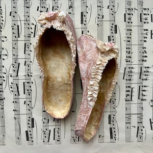 Una scarpetta da ballo in miniatura realizzata in carta riciclata con volant, fiocco e piccola rosa color crema o azzurro cielo