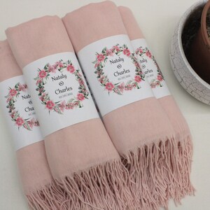 May include: Four pink pashmina shawls with floral designs and the text "Natly & Charles 03.05.2022" printed on the labels.