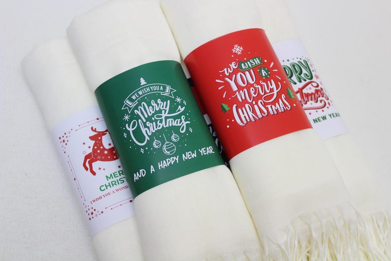 Pode incluir: Quatro sacos de presente de tecido branco com etiquetas de presente de papel com tema natalino. As etiquetas s&atilde;o de cor vermelha, verde e branca com texto escrito &agrave; m&atilde;o que diz "We wish you a Merry Christmas and a Happy New Year", "We wish you a Merry Christmas", "Merry Christmas", e "We wish you a Merry Christmas".