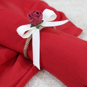 May include: A red scarf with a white ribbon and a red rose tied around it.