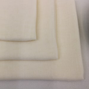 May include: Three layers of white fabric folded on top of each other. The fabric is smooth and has a subtle texture.
