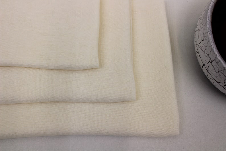 May include: Three layers of white fabric folded on top of each other. The fabric is smooth and has a subtle texture.