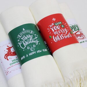 Pode incluir: Tr&ecirc;s sacos de presente de tecido branco com etiquetas de presente de papel com tema natalino. As etiquetas s&atilde;o de cor verde, vermelha e branca com texto de caligrafia manuscrito. O texto nas etiquetas diz "We wish you a Merry Christmas and a Happy New Year", "We wish you a merry Christmas", e "Merry Christmas and a Happy New Year".